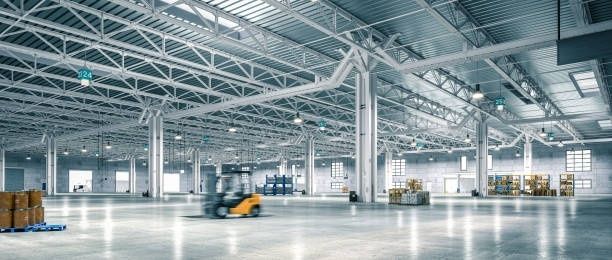 Helle Industriehalle mit Fördertechnik und Gabelstapler unter weitläufigem Stahldach